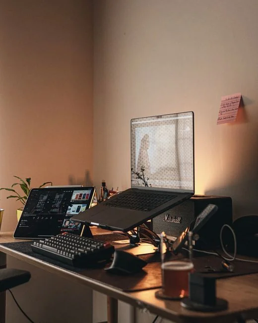 Un homme retouche l'image d'un fruit sur un MacBook Pro tout en étant assis dehors sur l'herbe.